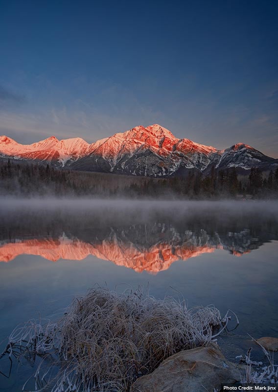 A view across a misty lake toward a snow-dusted mountain.