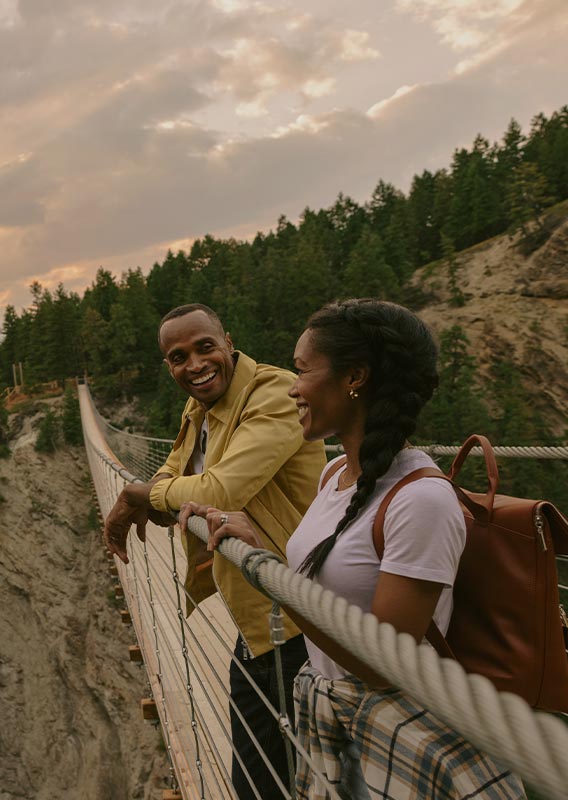 Two people on a suspension bridge stretching across a canyon