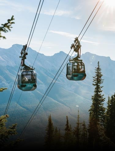 Two gondola cabins pass each other above a mountainside.