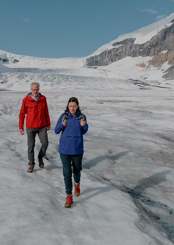 Two people walking on a glacier.