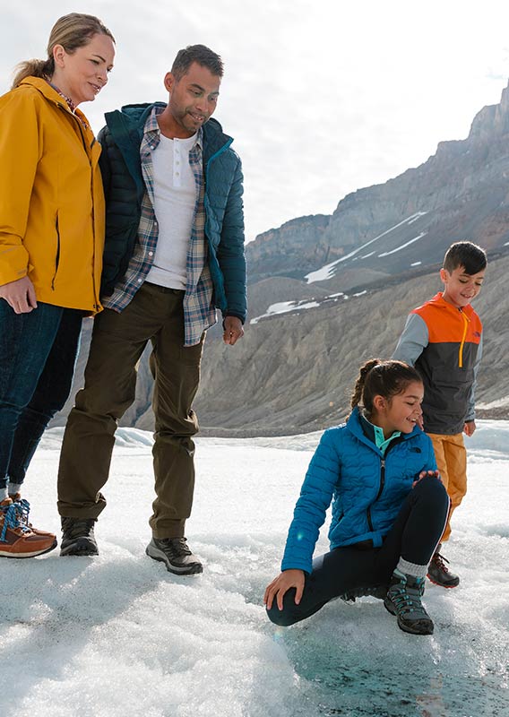 A family looks and crouches near the ice field.