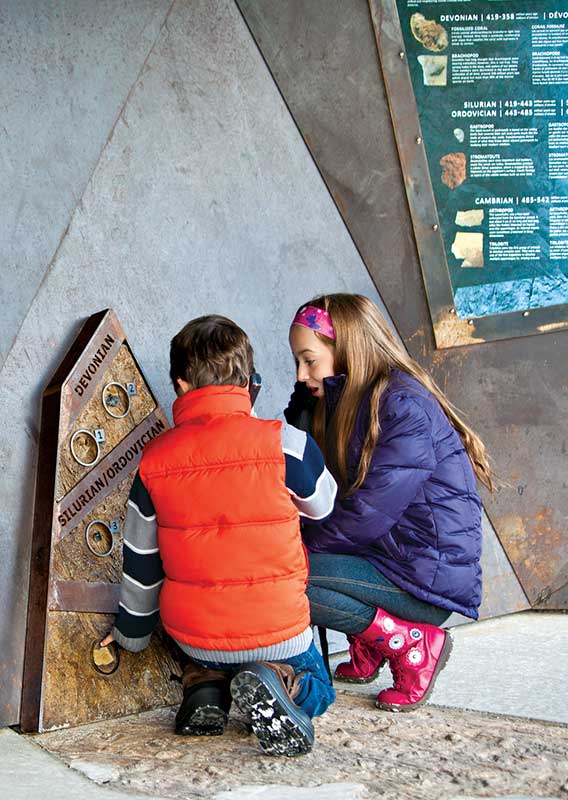 Children exploring the interpretive area of the Columbia Icefield Skywalk listening to an audioguide