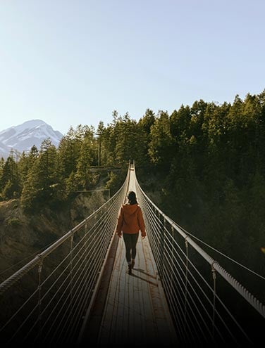 A person walks across a long suspension bridge.