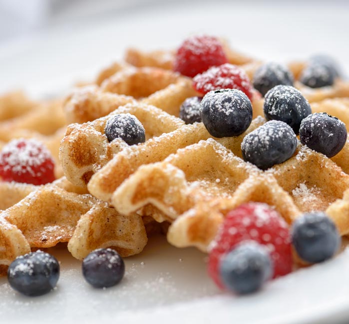 Waffles topped with icing sugar, blueberries and raspberries