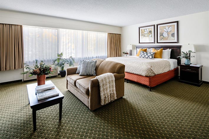 A king bed, couch and coffee table in a large hotel room