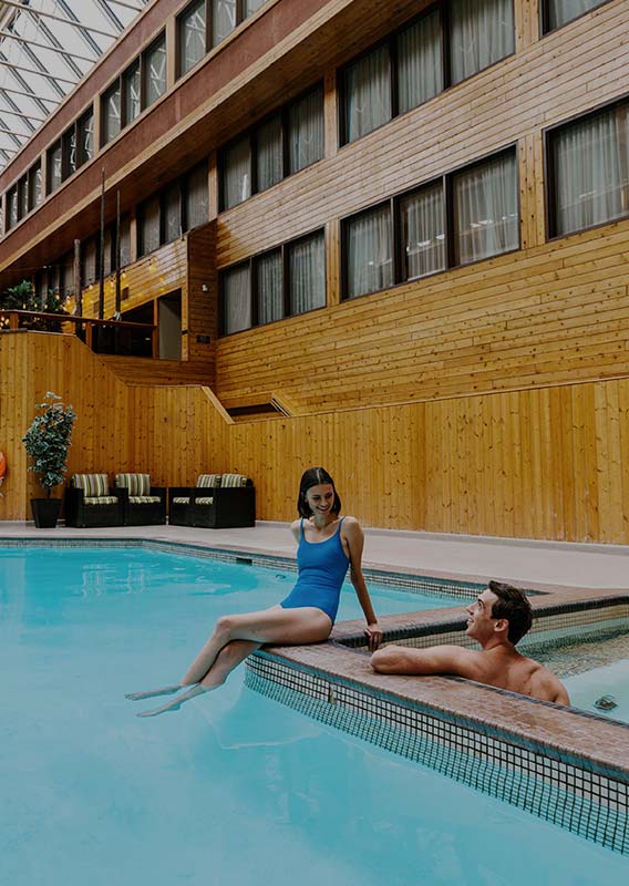 Two people relax at a swimming pool edge.