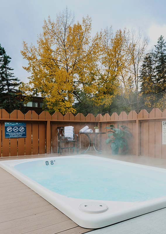 A hot tub on a wooden deck surrounded by trees with autumn colours.