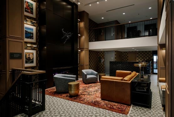 A tall lobby with leather lounge chairs and couches.
