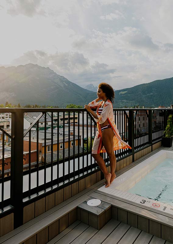 A woman stands at a rooftop balcony next to a hot tub