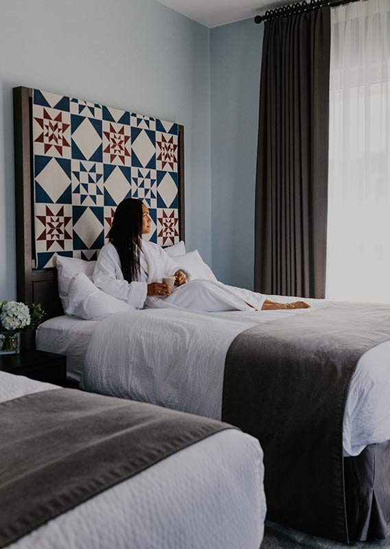 A woman lounges on a bed in a modern hotel room.