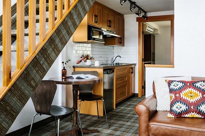 A hotel room kitchen below a wooden staircase.