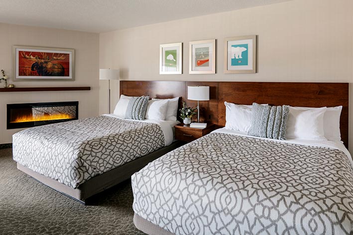 Two beds in a hotel room with a fireplace beside them