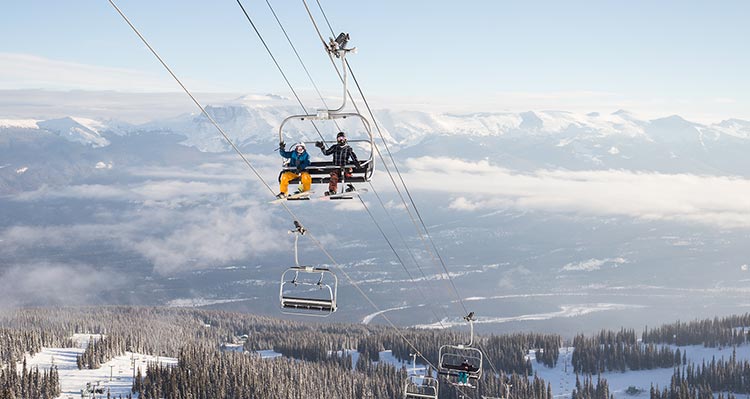Two people with snowboards sit on a chairlift.