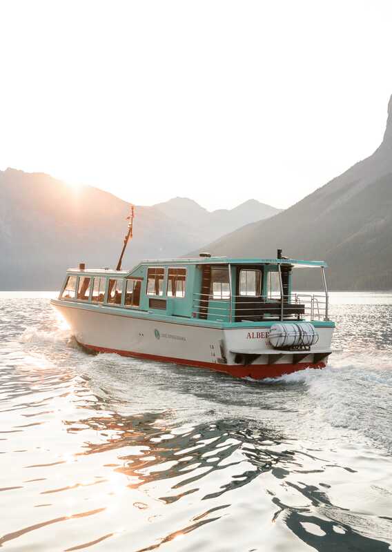 A tour boat on the water passing by the mountains