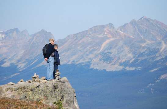 Couple standing at cliff, looking at mountain view