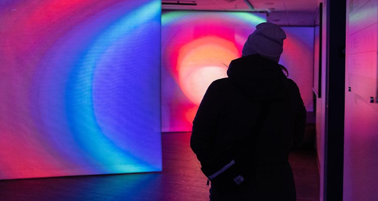A person walks through a room with glowing lights against the walls.
