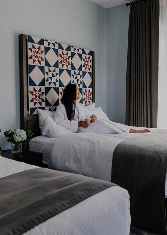 A woman relaxing on a hotel bed.