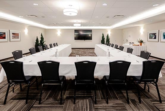 A conference room set up with a u-shaped table.