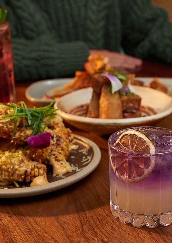 A table of meals featuring a purple cocktail.