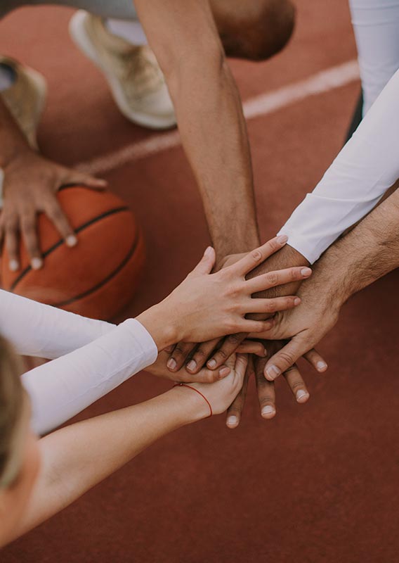 A sports team puts their hands together for a cheer.