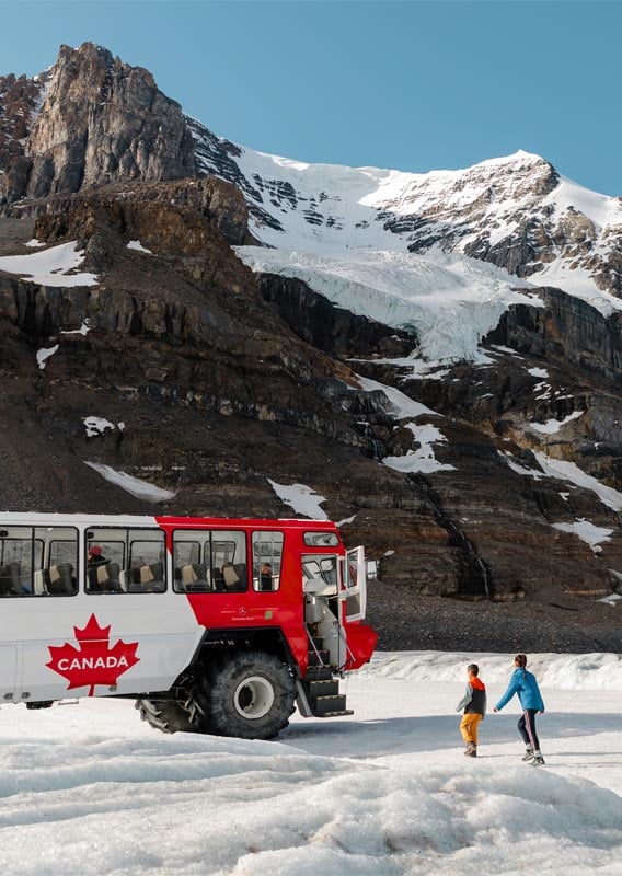 Two visitors walking toward the Ice Explorer in the Columbia Icefield