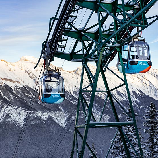 Two gondola cabins going up the mountain in winter.