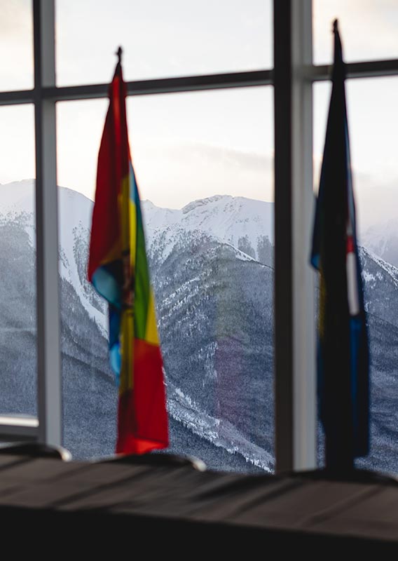 A row flags against a window overlooking snow-covered mountains.