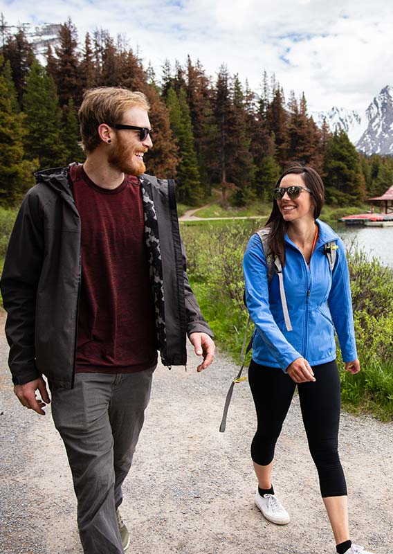 Two people walk on a lakeside trail