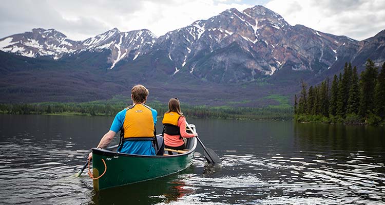 Two adults canoeing with mountains in the background