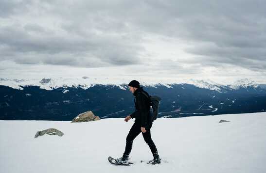 Person snowshoeing across mountain peak