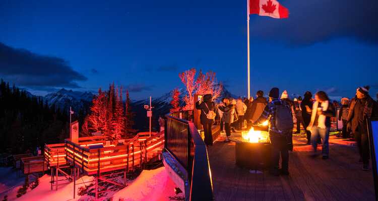 People standing around a fire pit at Banff Gondola Nightrise