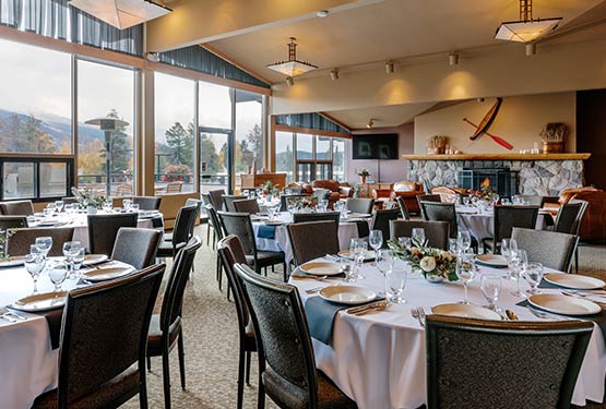 A large dining room with many round banquet tables set up.