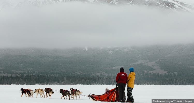 A dog sled pulling some people across a frozen landscape..