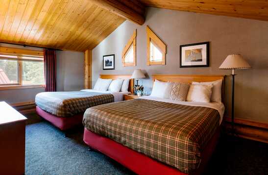 Two beds in a wooden cabin bedroom.