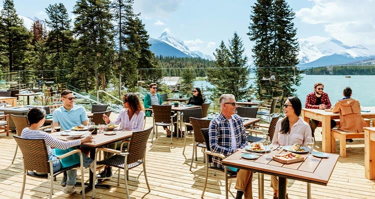 A patio with lots of people sitting at dining tables.