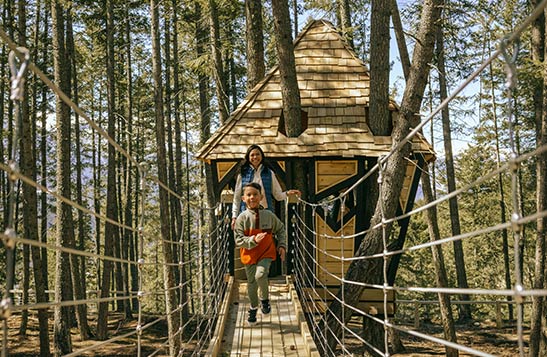 Mother and young son walk across a wooden skybridge