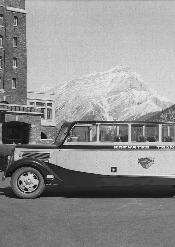 A historic style bus with mountains in the background.